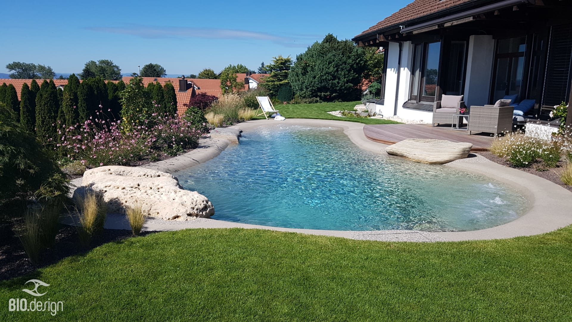 Bio.design Pool – organische Form mit Holzdeck und Sitzstein